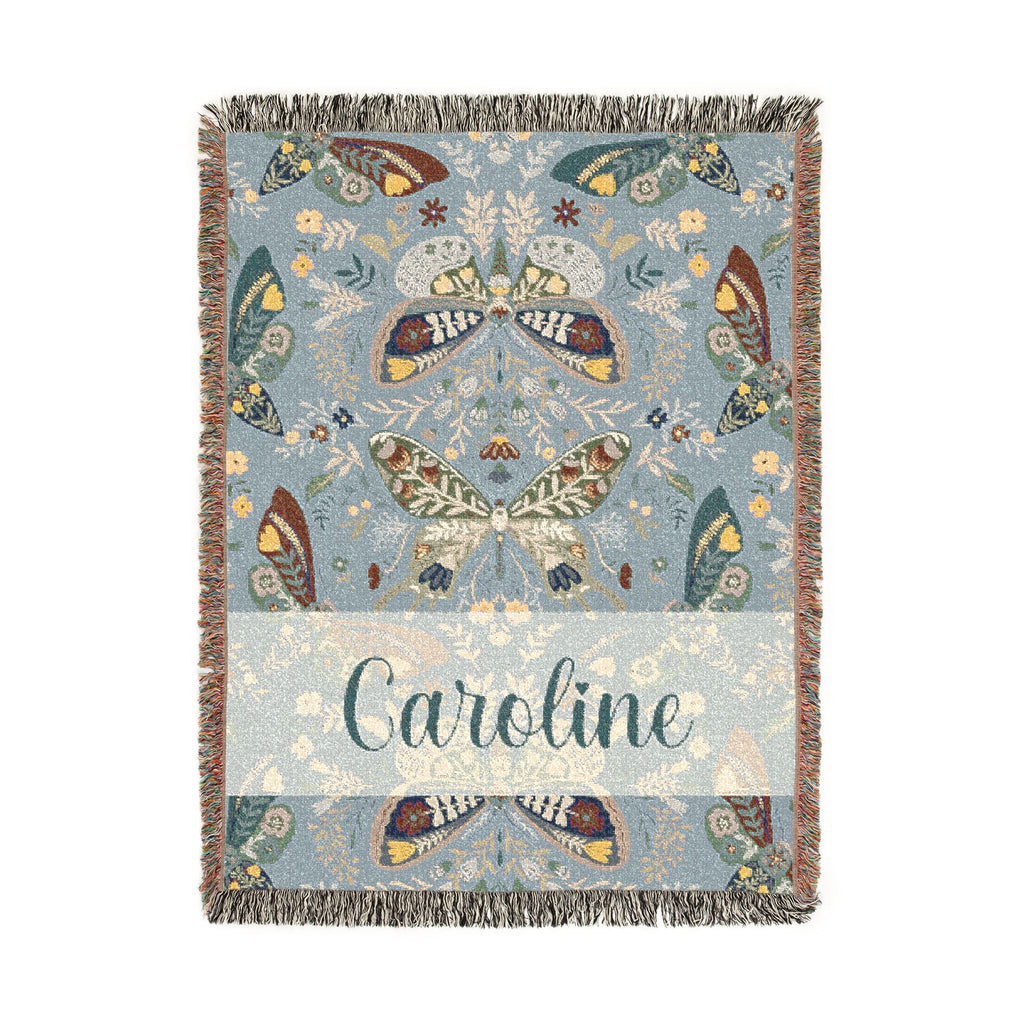 Decorative blanket with butterfly pattern and 'Caroline' text on a light blue background