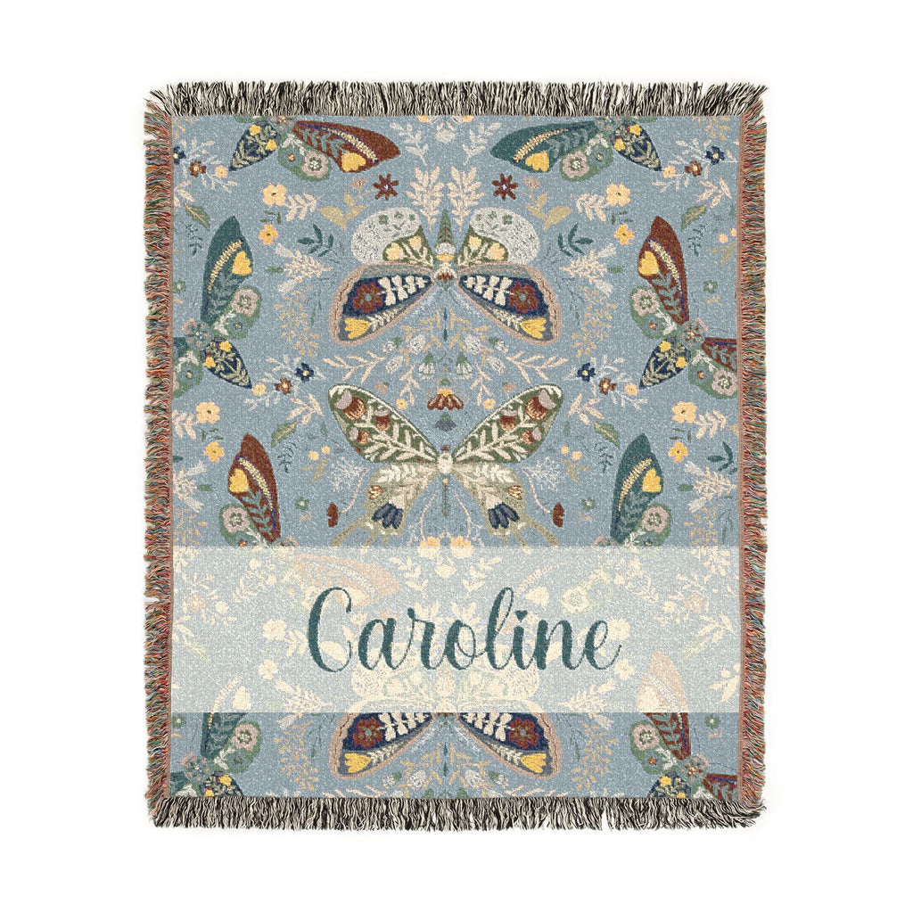 Decorative blanket with butterfly pattern and 'Caroline' text on a light blue background