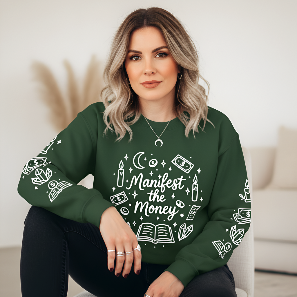 Woman wearing a green sweatshirt with 'Manifest the Money' design sitting on a couch.