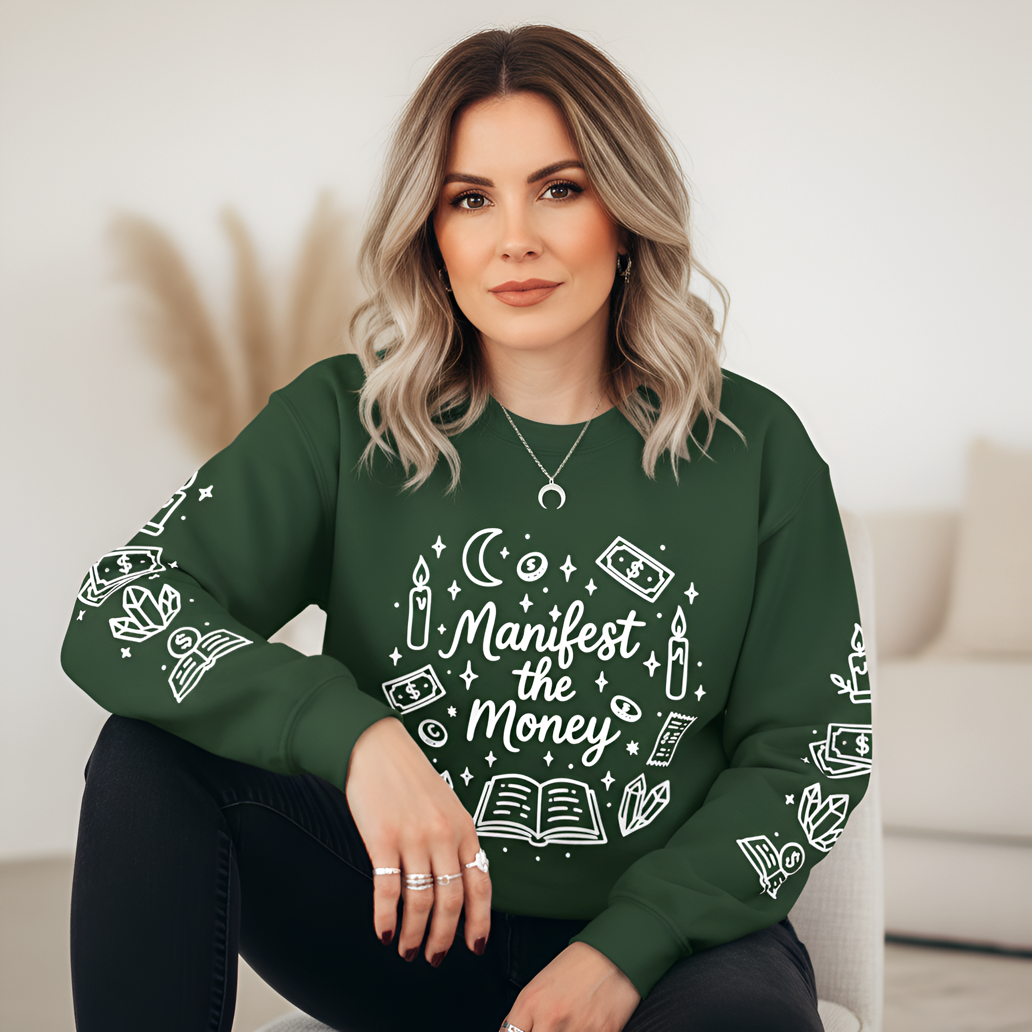 Woman wearing a green sweatshirt with 'Manifest the Money' design sitting on a couch.