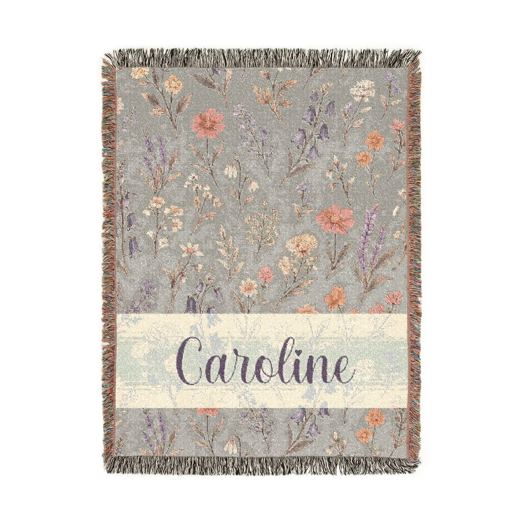 Floral patterned throw blanket with 'Caroline' text on a light background