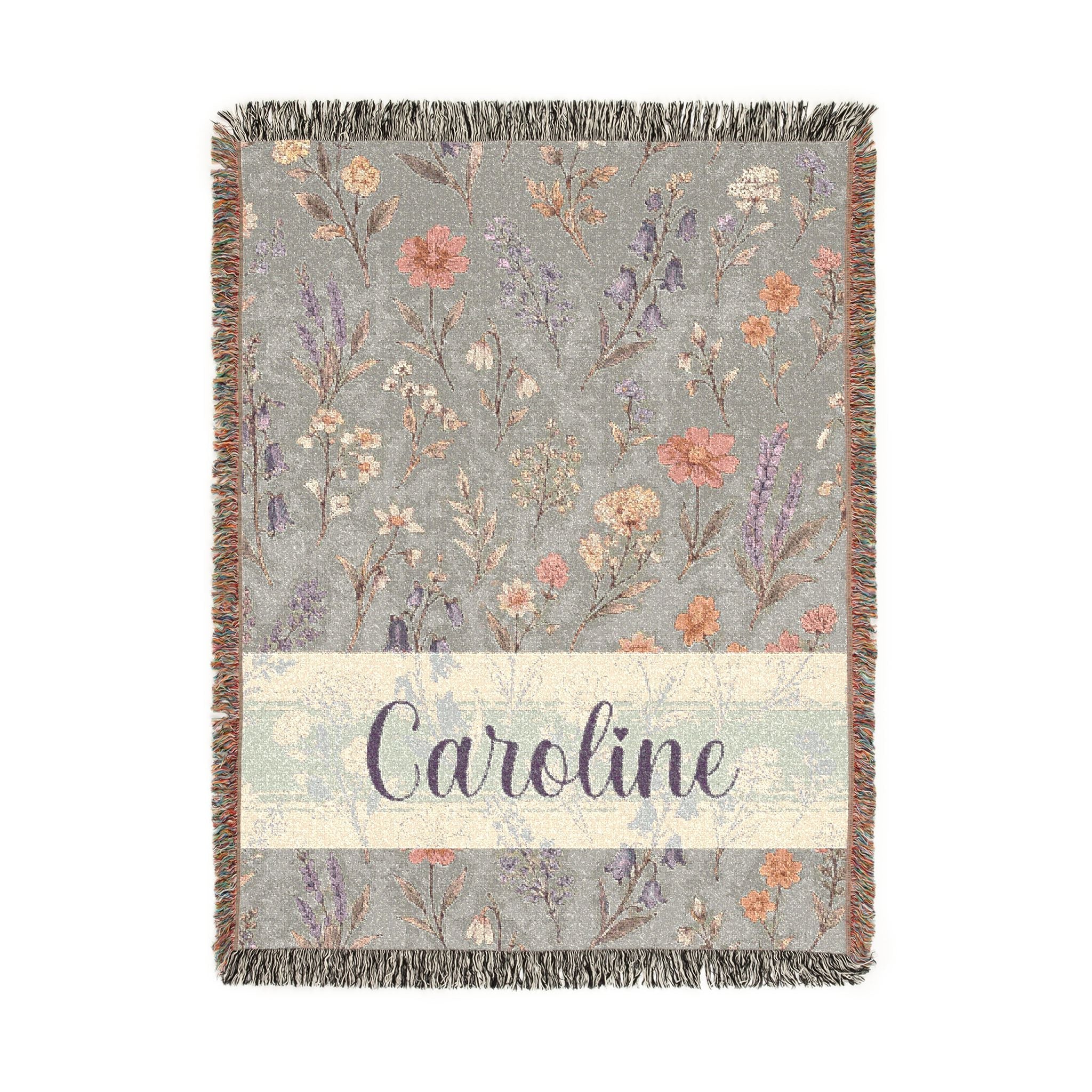 Floral patterned throw blanket with 'Caroline' text on a light background