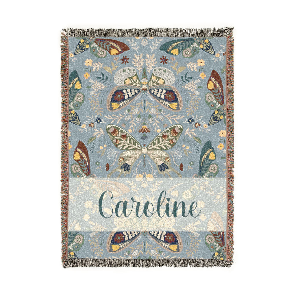 Decorative blanket with butterfly patterns and the name 'Caroline' on a light blue background