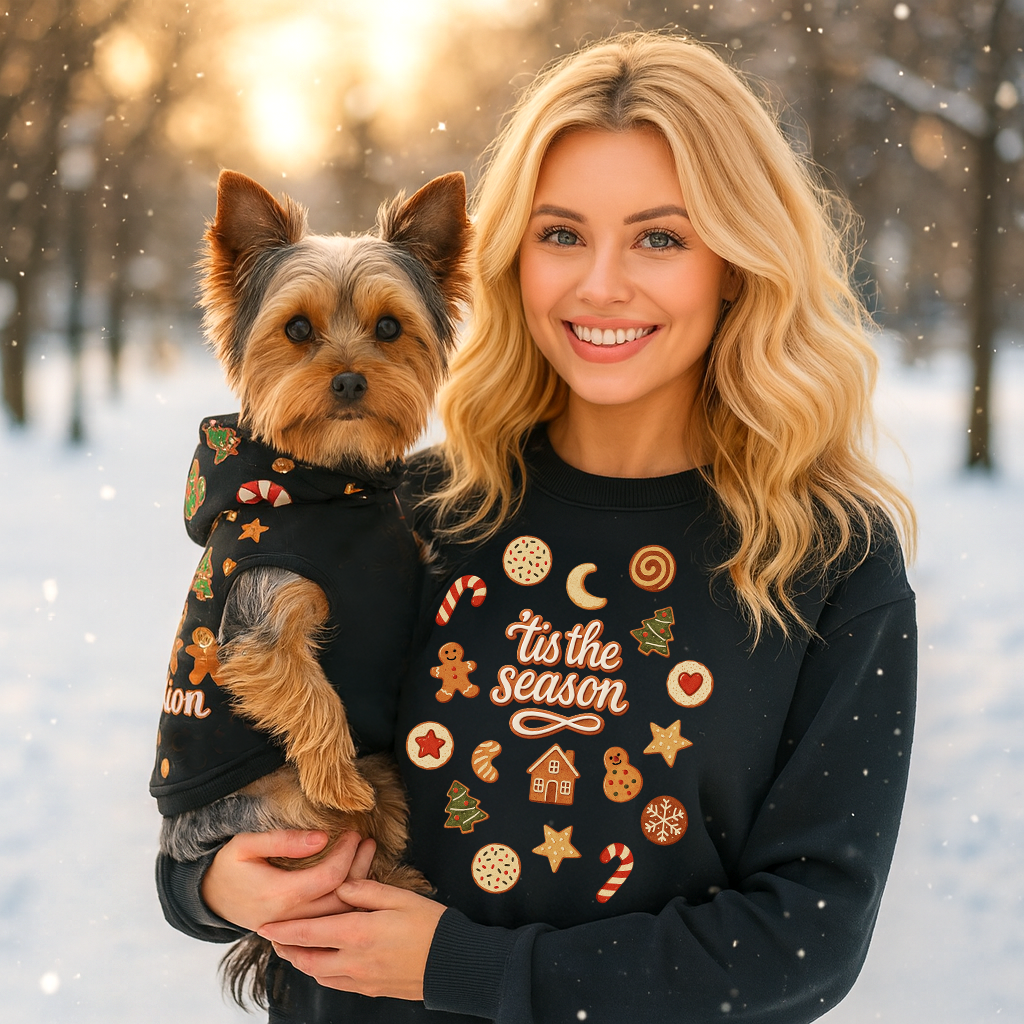 Woman holding a dog in a winter setting with festive text on their clothing