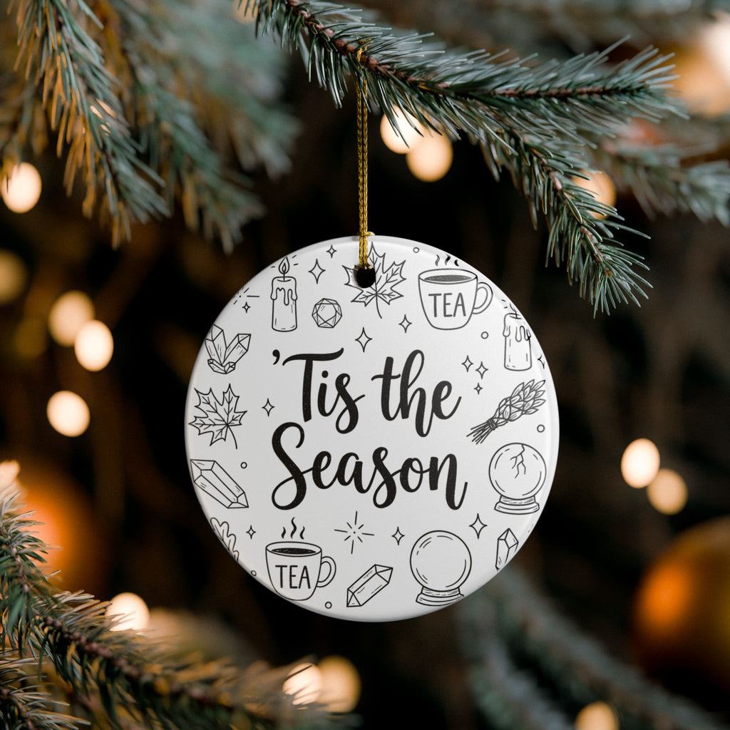 Decorative ornament with 'Tis the Season' text hanging on a Christmas tree.