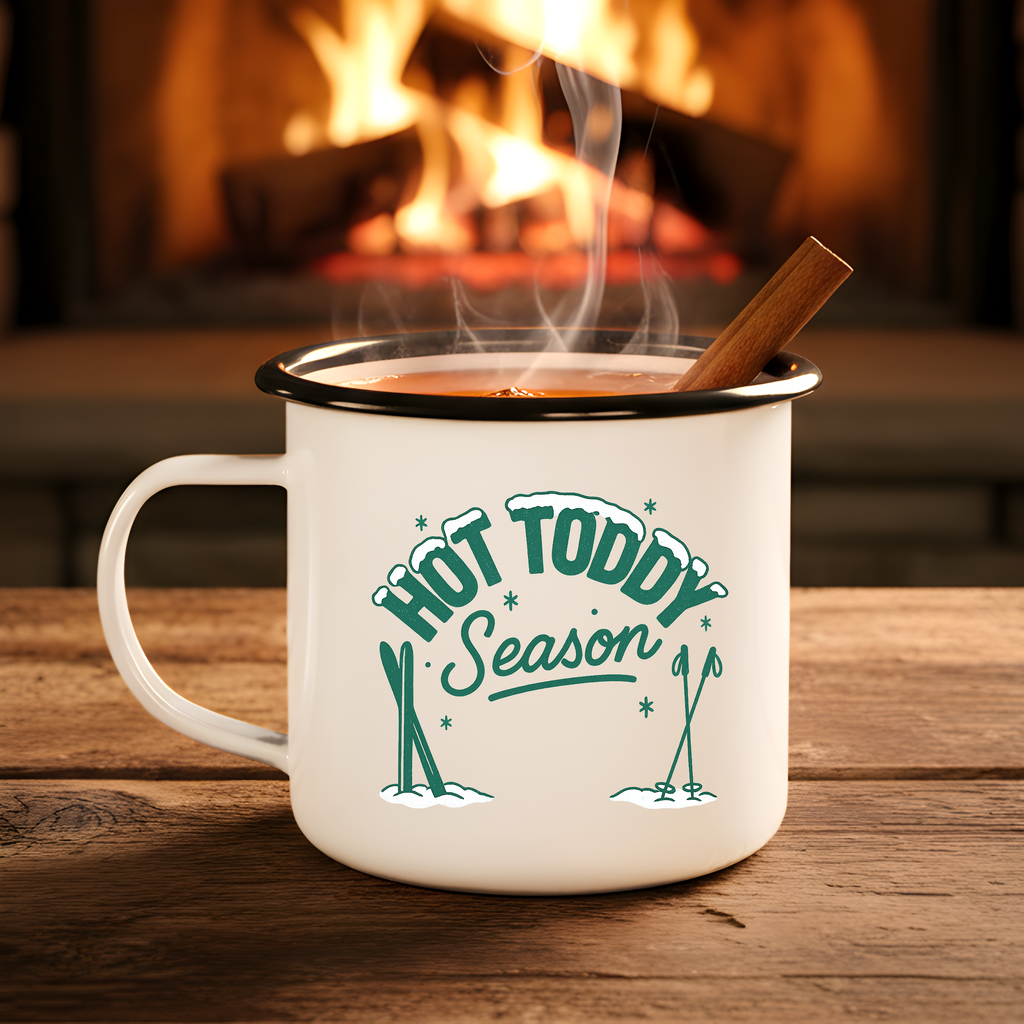 Mug with 'Hot Toddy Season' text in front of a fireplace