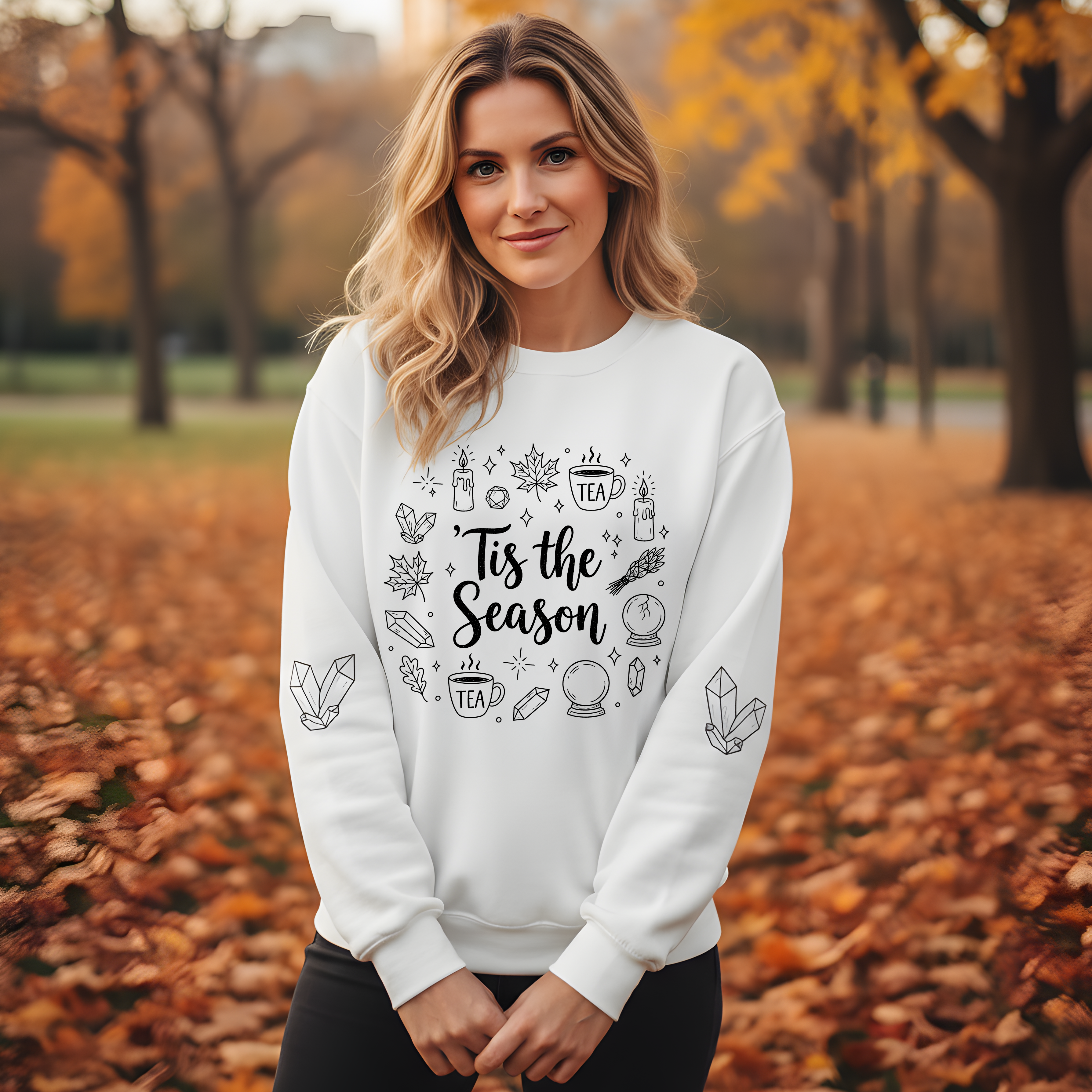 Woman wearing a white sweatshirt with a seasonal design in an autumn park.