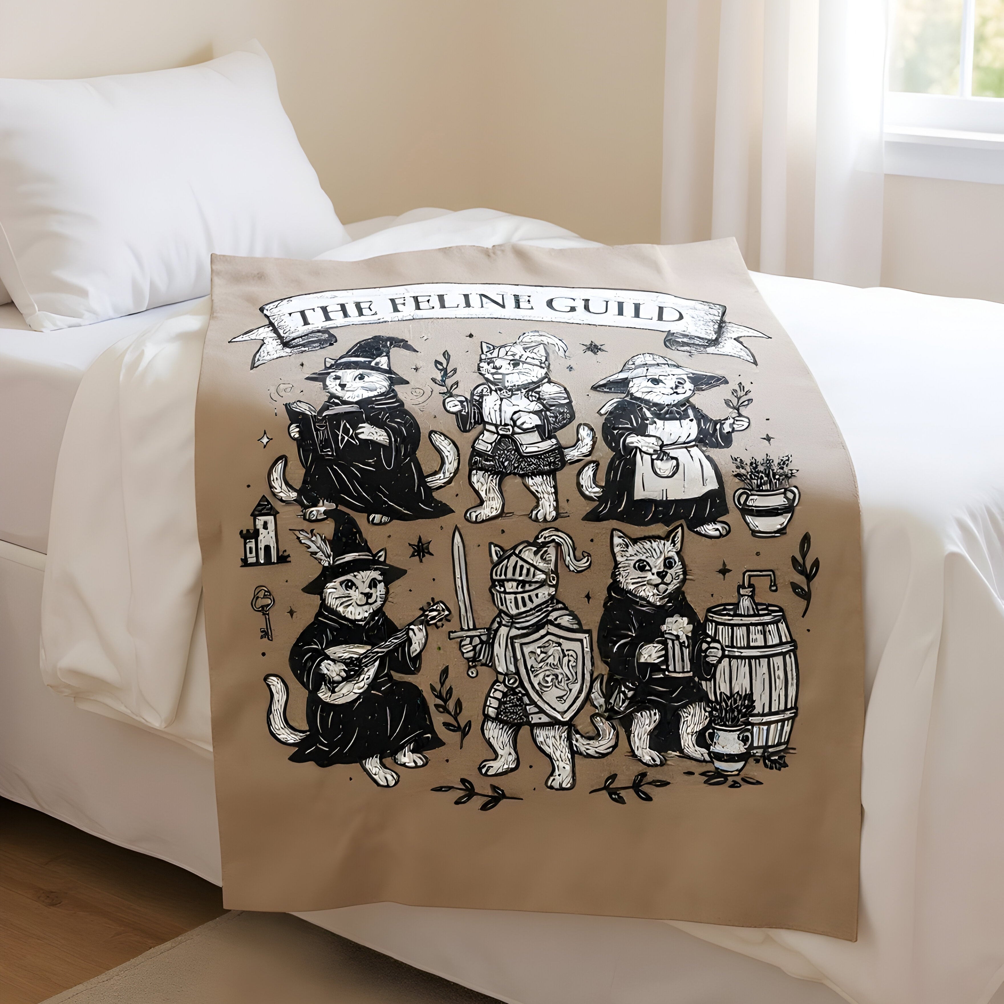 Beige blanket with black and white cat illustrations and 'The Feline Guild' text on a bed.